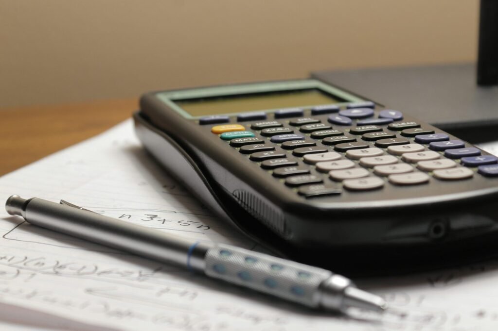 Calculator and pen resting on a page of handwritten figures