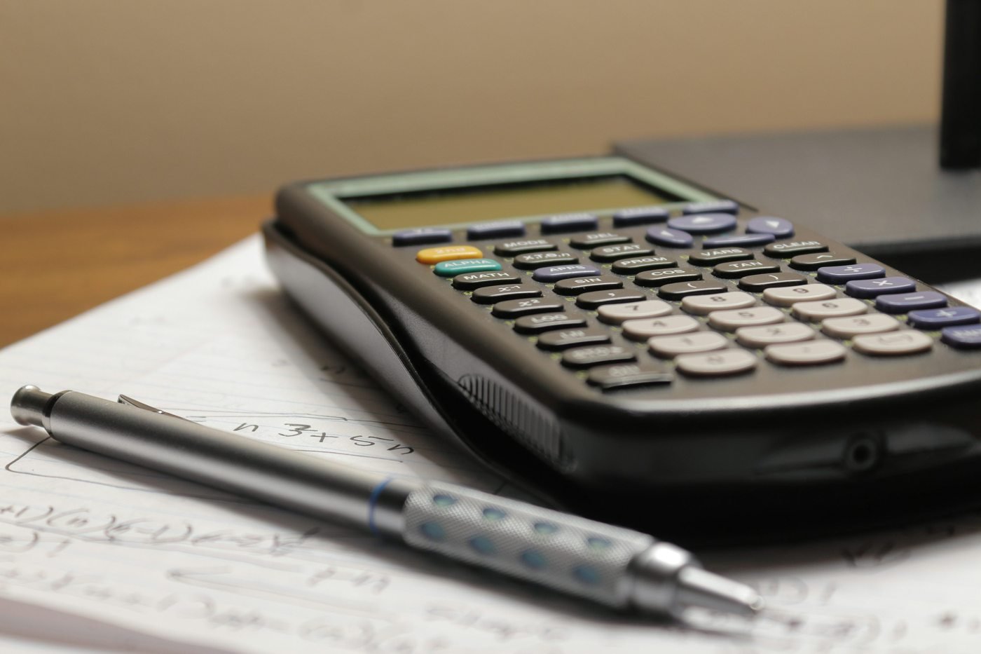 Calculator and pen resting on a page of handwritten figures