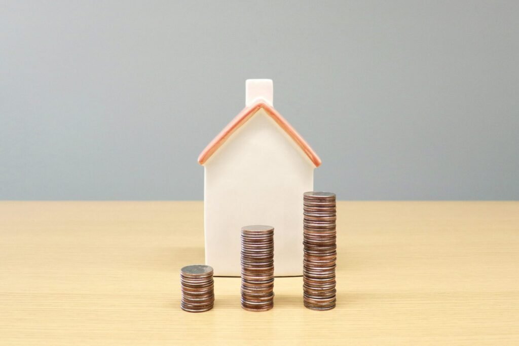 Small model house beside three stacks of coins