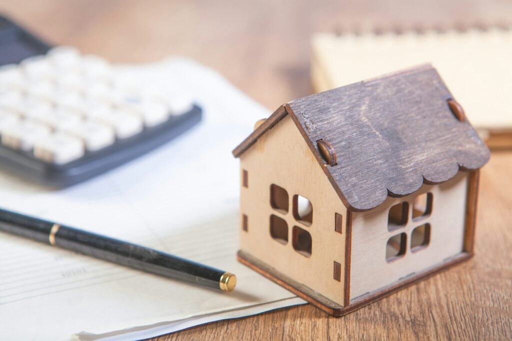 Small model house beside a calculator, notebook and pen