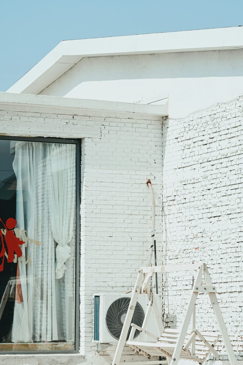 Outdoor air conditioning unit beside a white brick house during installation.