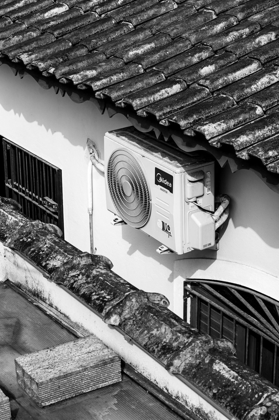Outdoor air conditioning unit mounted beneath the roof of a house.
