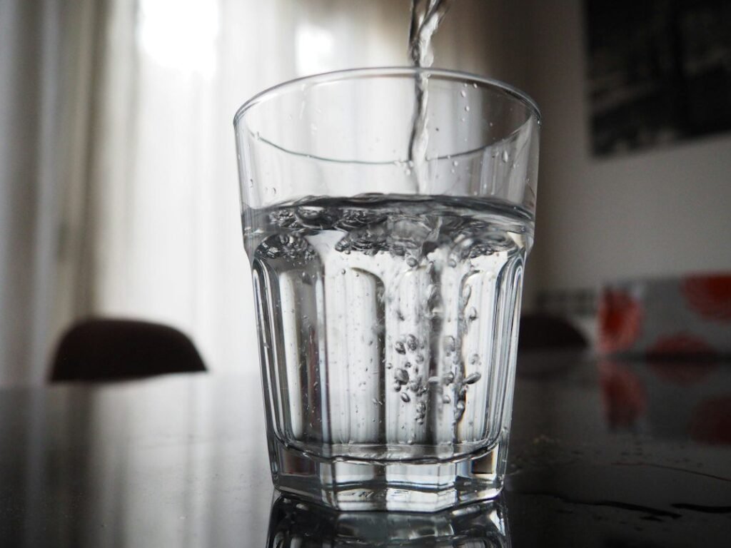 Water being poured into a clear drinking glass.