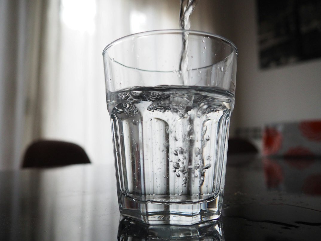Water being poured into a clear drinking glass.