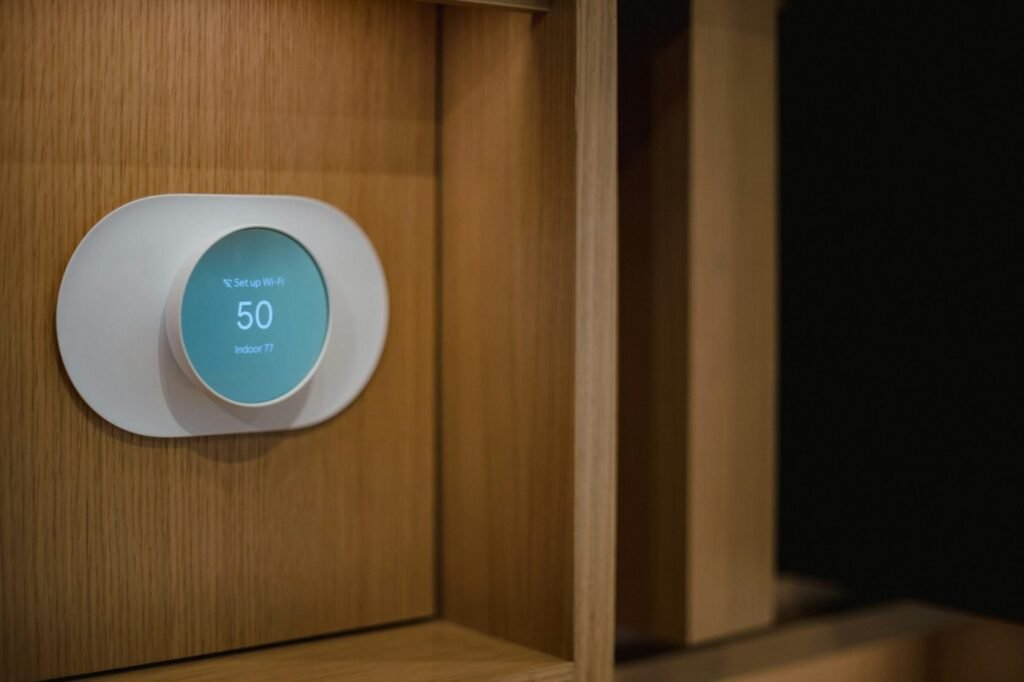 Wall-mounted home thermostat showing the set temperature below the indoor temperature