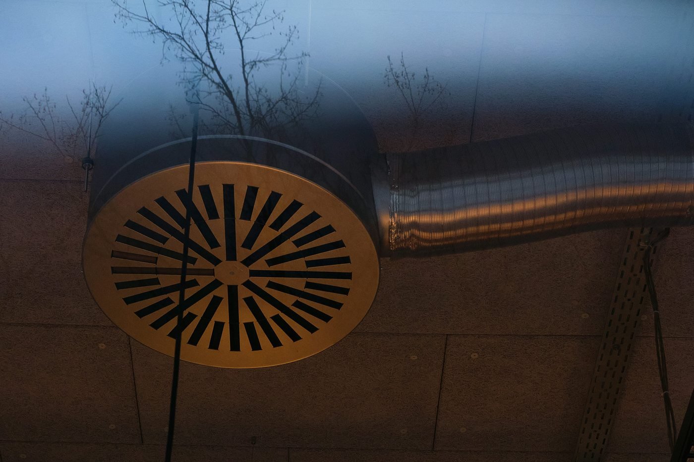 Round metal ceiling air vent connected to exposed ductwork