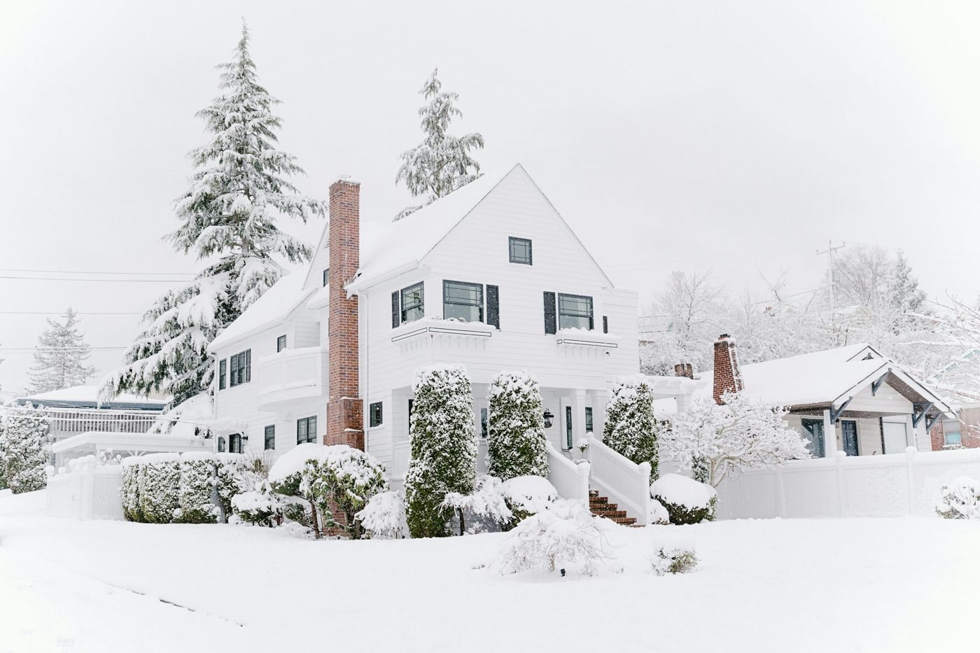White house and evergreen trees covered in fresh winter snow
