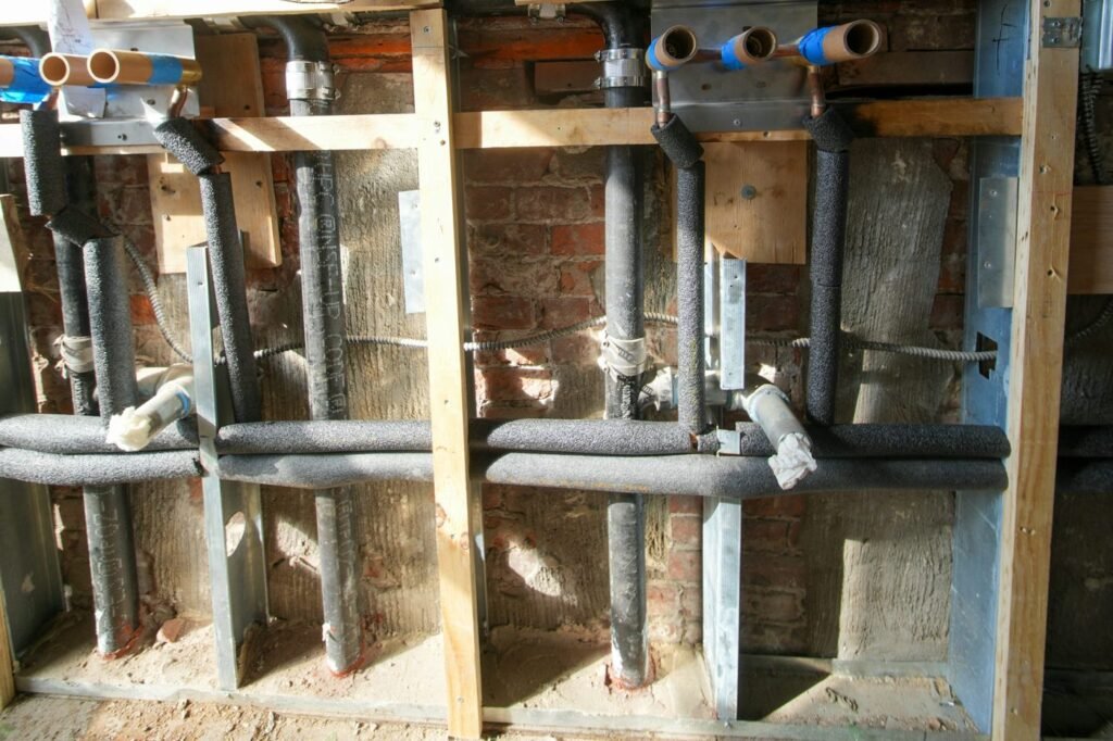 Insulated water supply pipes and drain connections inside exposed wall framing