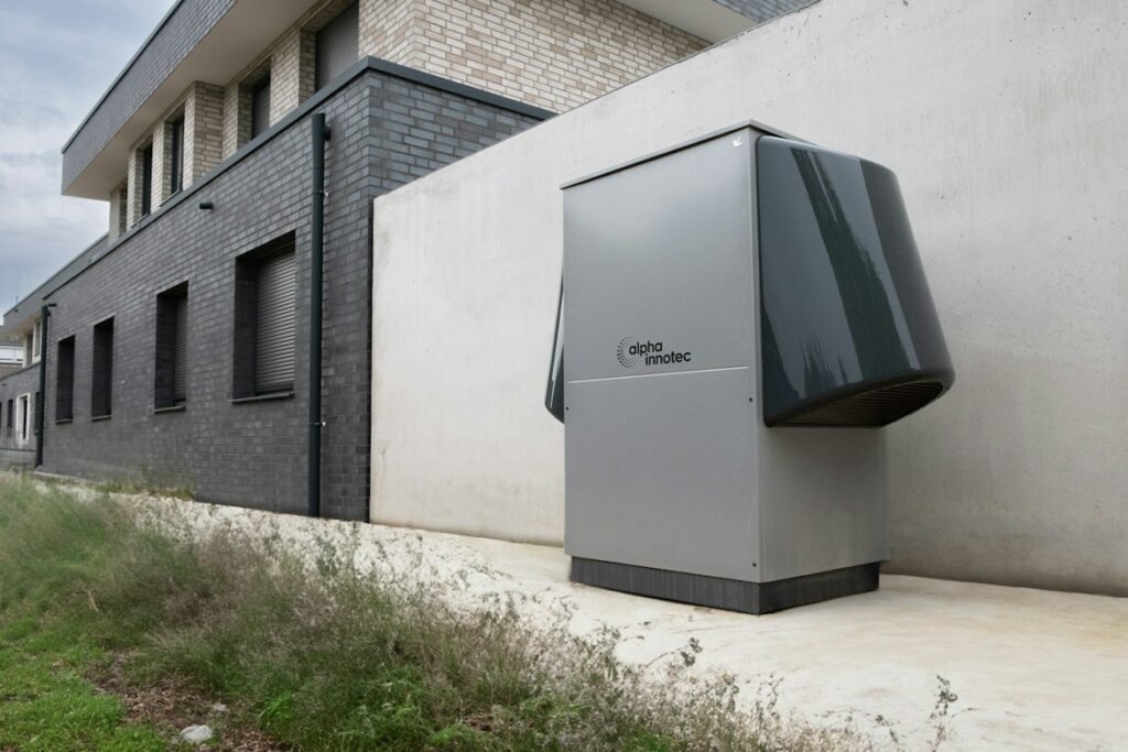 Outdoor air-to-water heat pump installed beside a brick home.