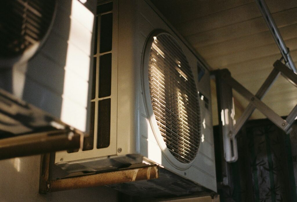 Outdoor air conditioning unit mounted beside a home in afternoon light.