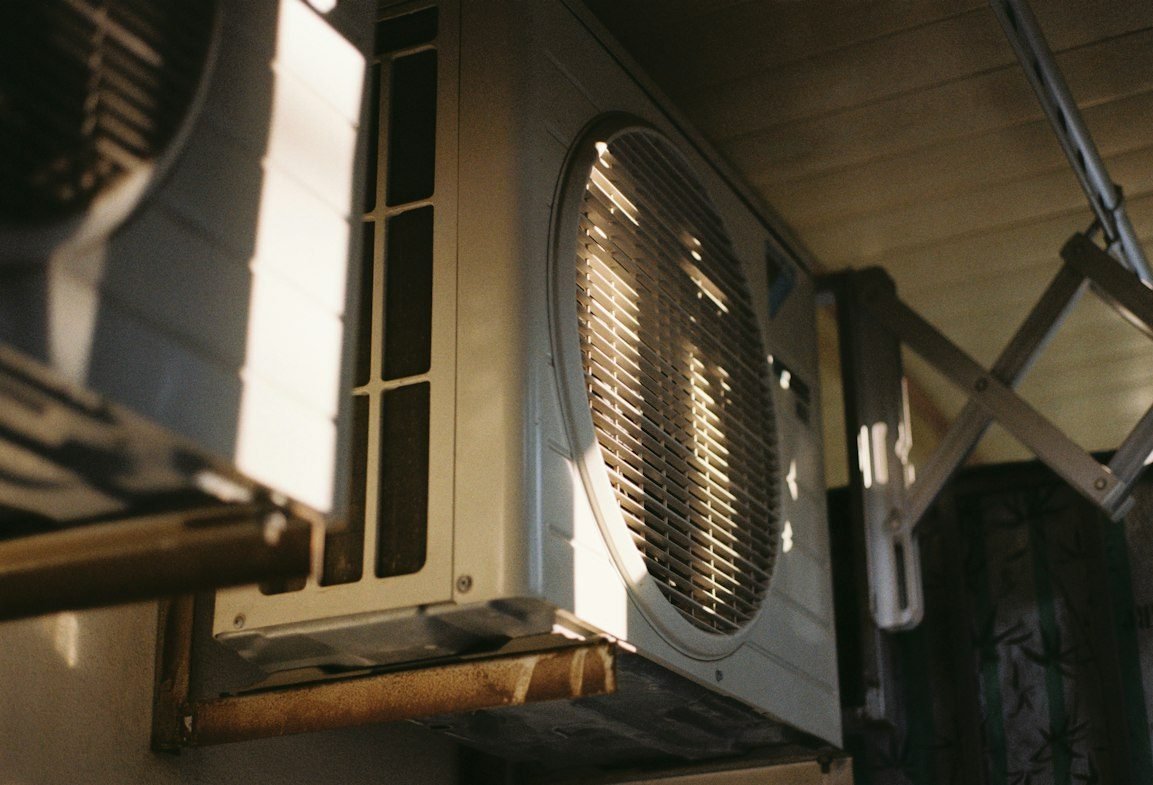 Outdoor air conditioning unit mounted beside a home in afternoon light.