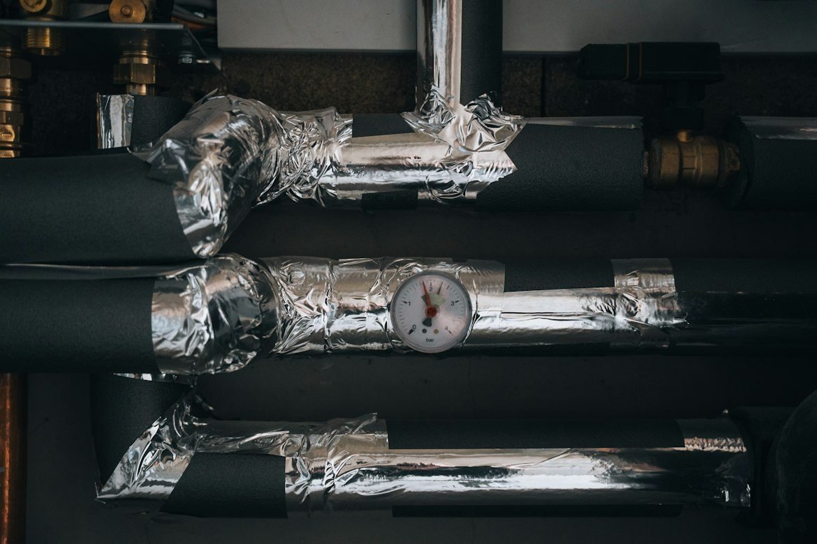 Insulated heating pipes and a pressure gauge in a mechanical room.