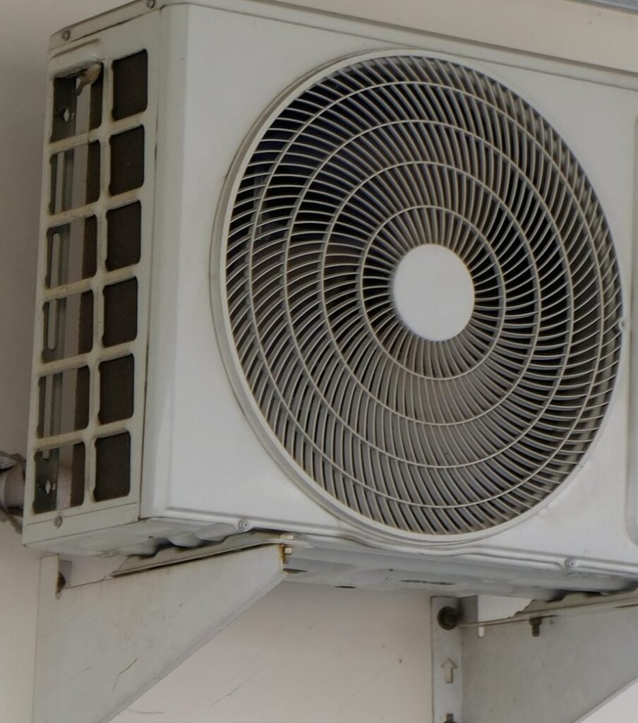 Close view of an outdoor air conditioner fan grille and mounting bracket