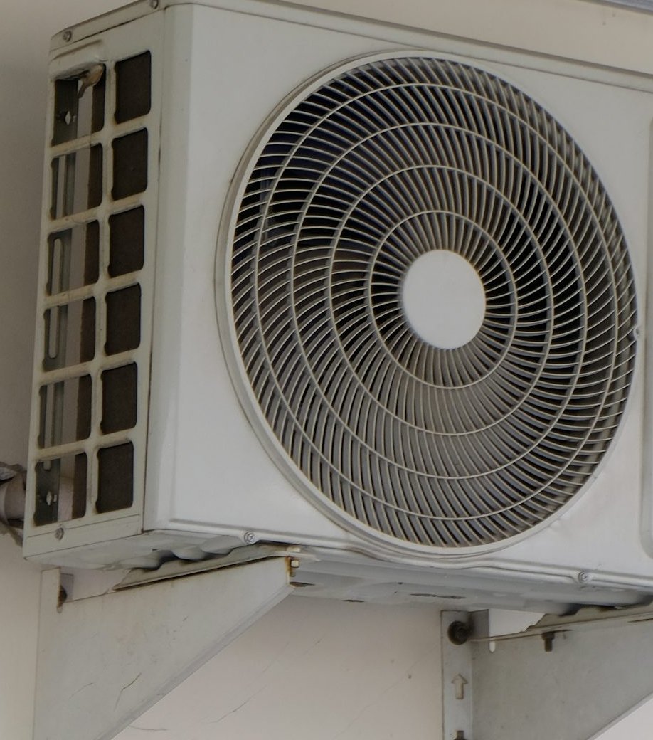 Close view of an outdoor air conditioner fan grille and mounting bracket