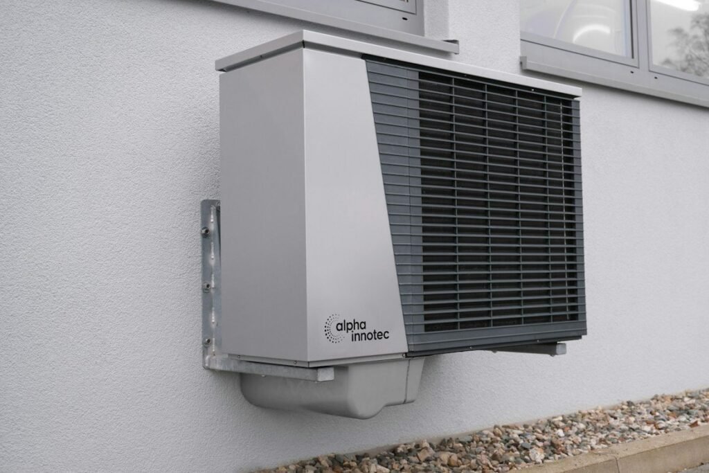Outdoor heat pump mounted on a white home exterior.