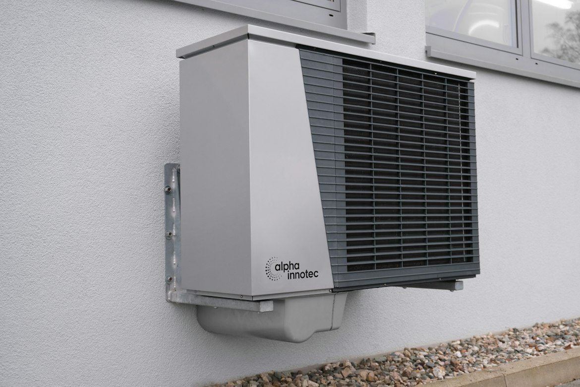 Outdoor heat pump mounted on a white home exterior.