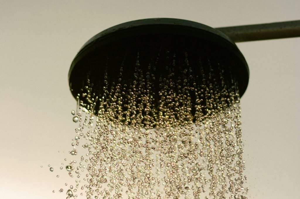 Water droplets falling from a dark round shower head