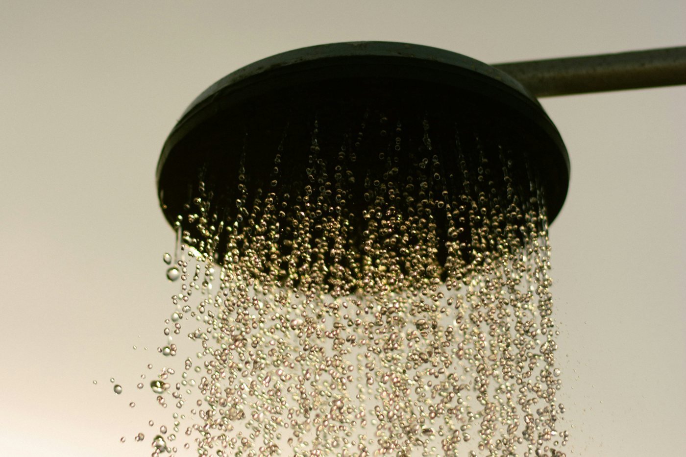 Water droplets falling from a dark round shower head