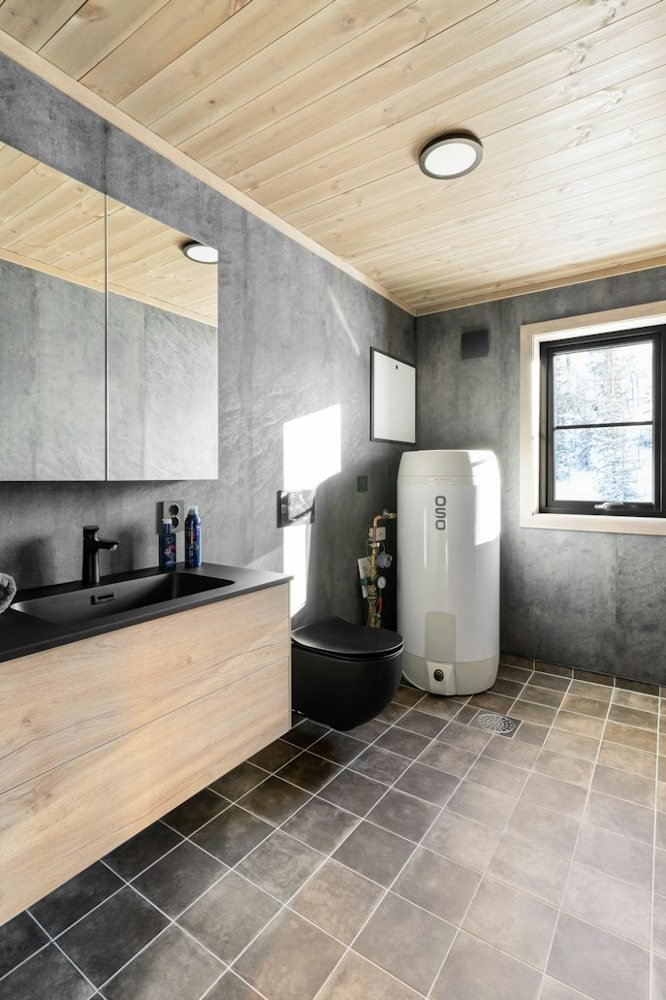 White cylindrical water heater installed in a tiled bathroom.