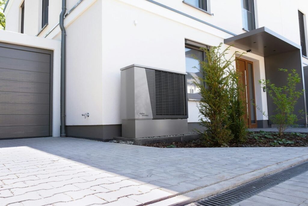 Outdoor heat pump installed beside the entrance of a modern house.