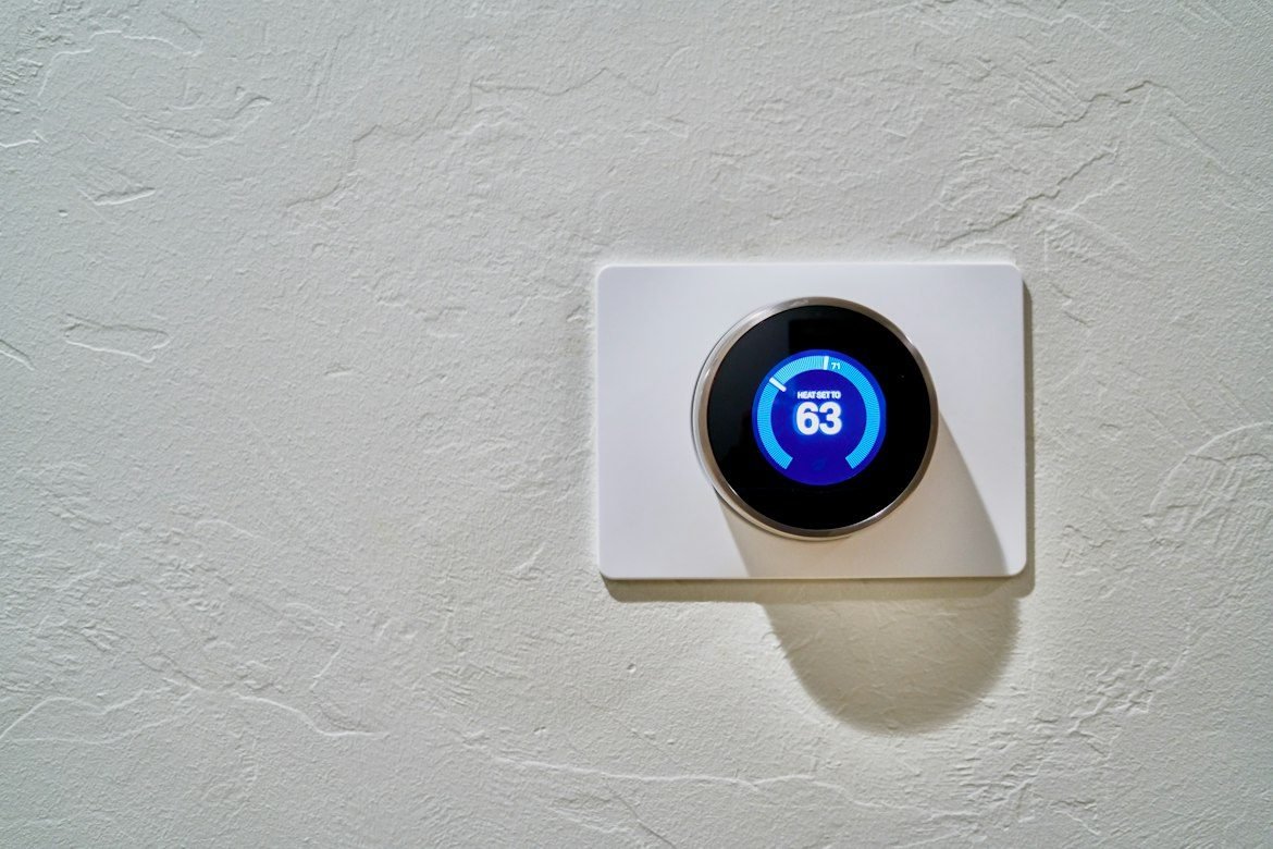 Digital home thermostat set to 63 degrees Fahrenheit.