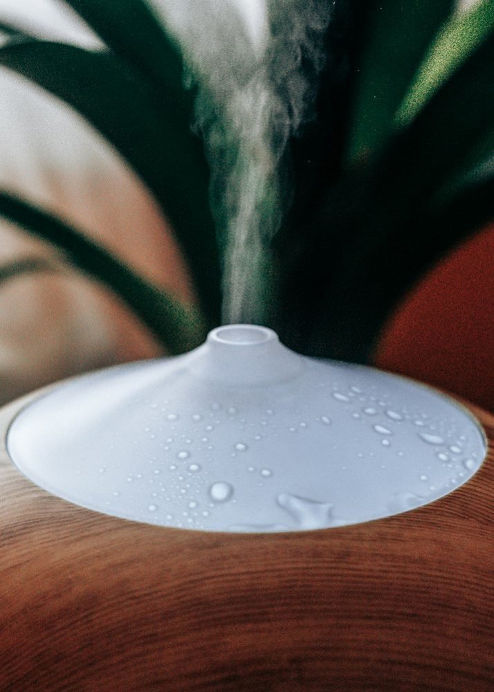 White home humidifier releasing mist from a wooden table.