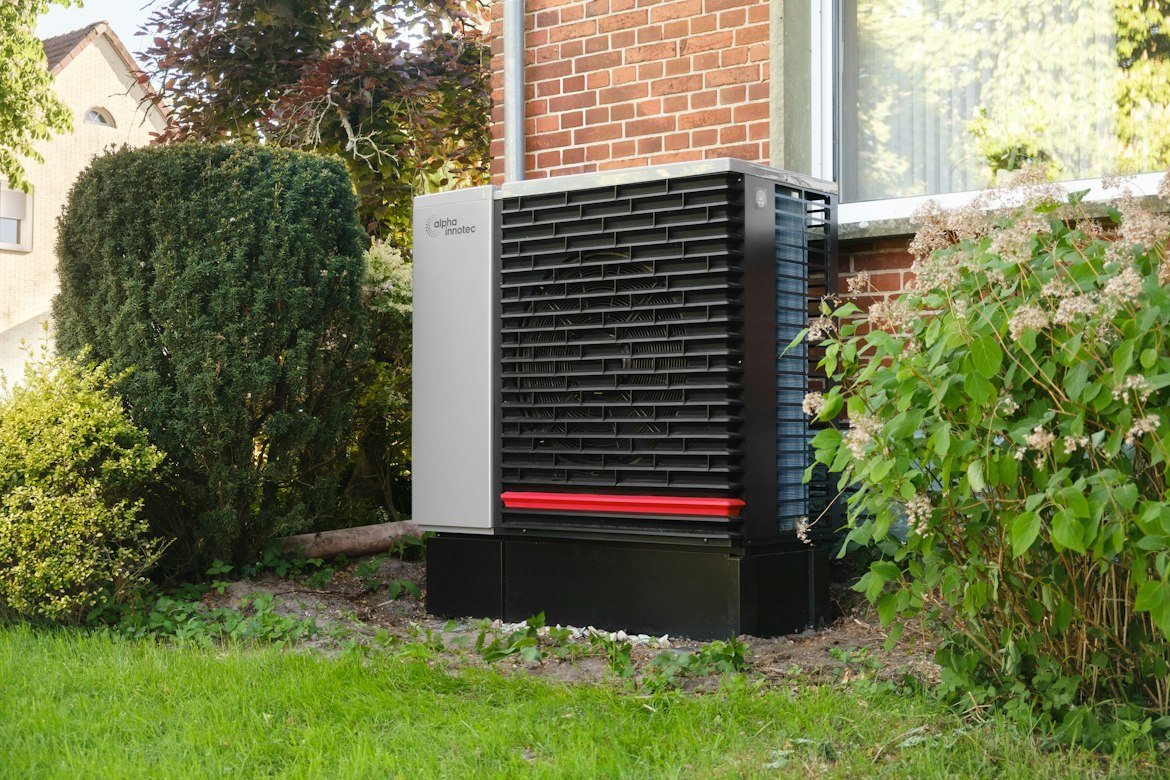 Residential outdoor heat pump installed beside a brick house.