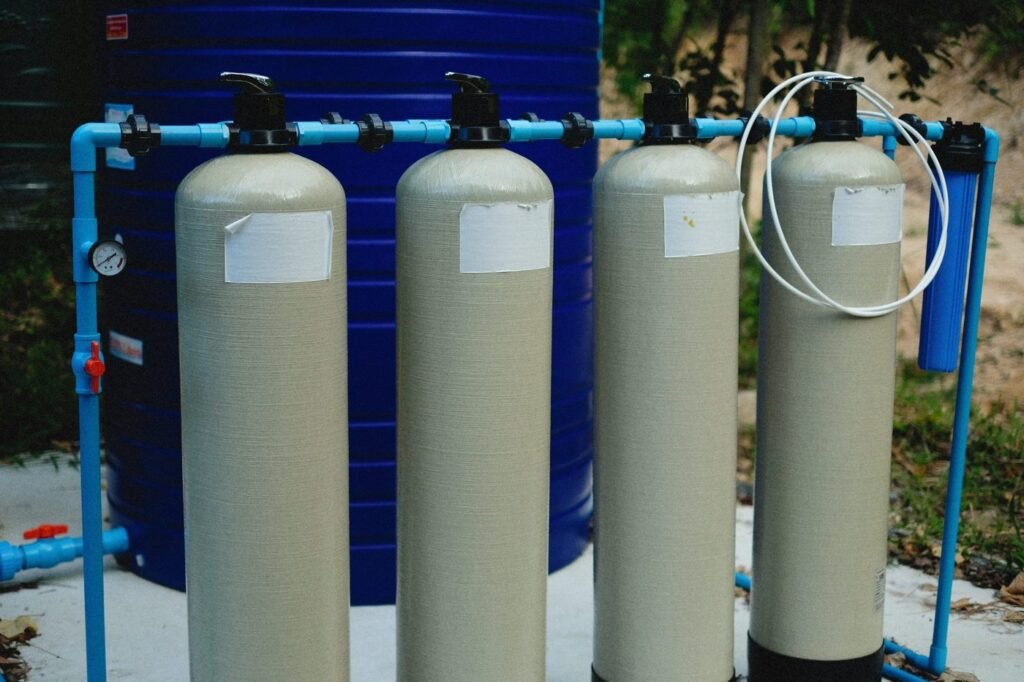 Water-treatment tanks connected to blue pipes outdoors.