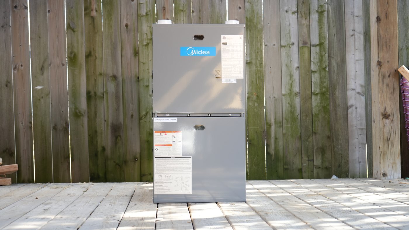 Gray furnace cabinet standing on a wooden deck before installation.